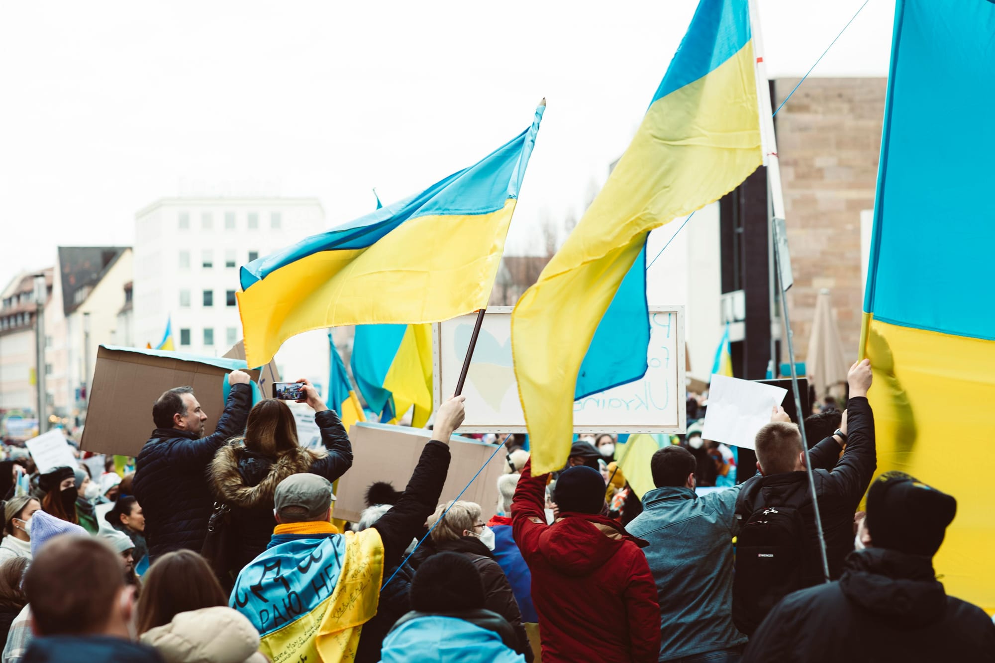 Pro-Ukraine demonstration: A crowd waves Ukrainian flags and holds protest signs in solidarity.