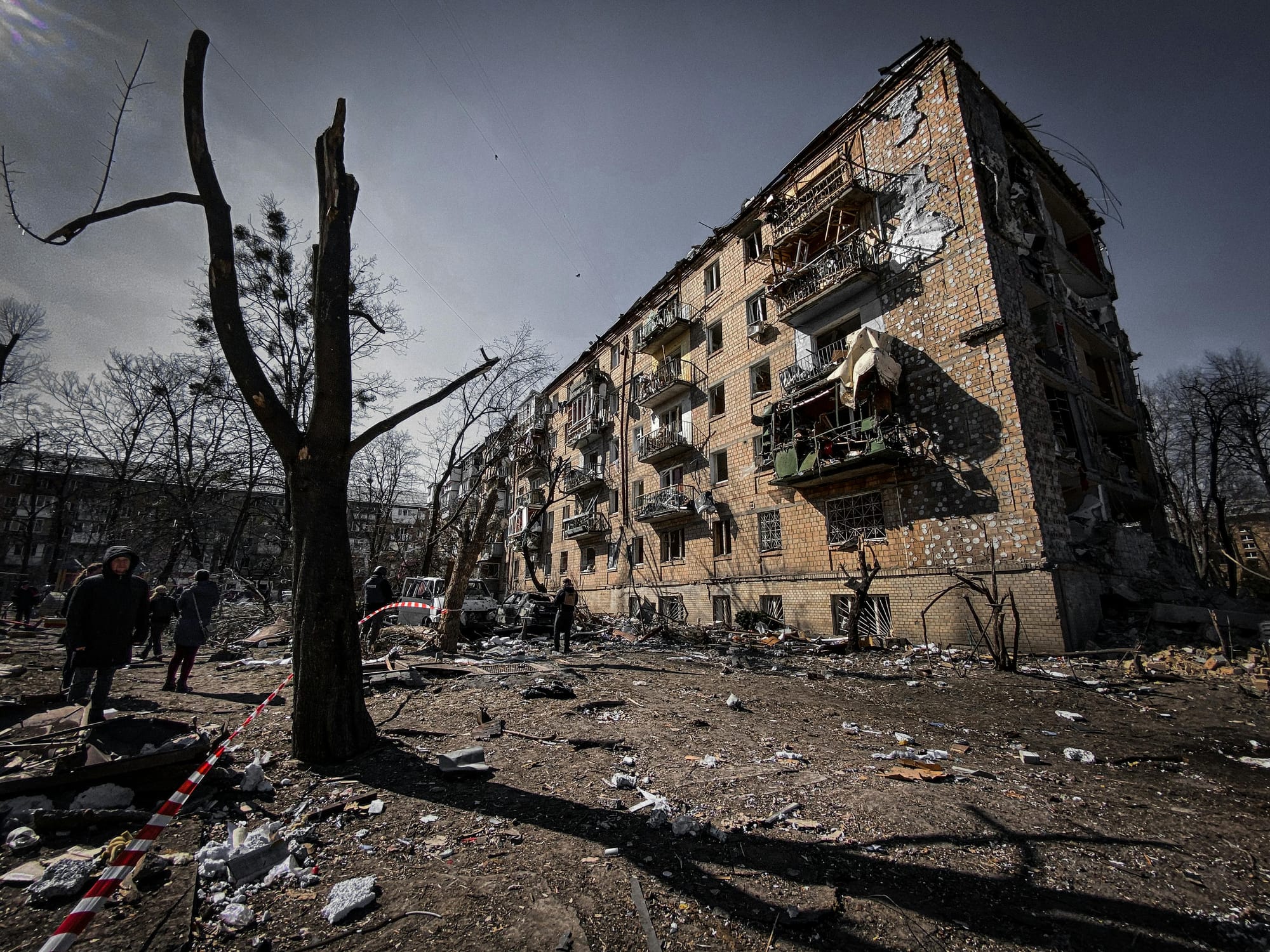 War-torn Ukraine: A destroyed residential building after a Russian drone strike, with debris, shattered windows, and civilians amid the wreckage.