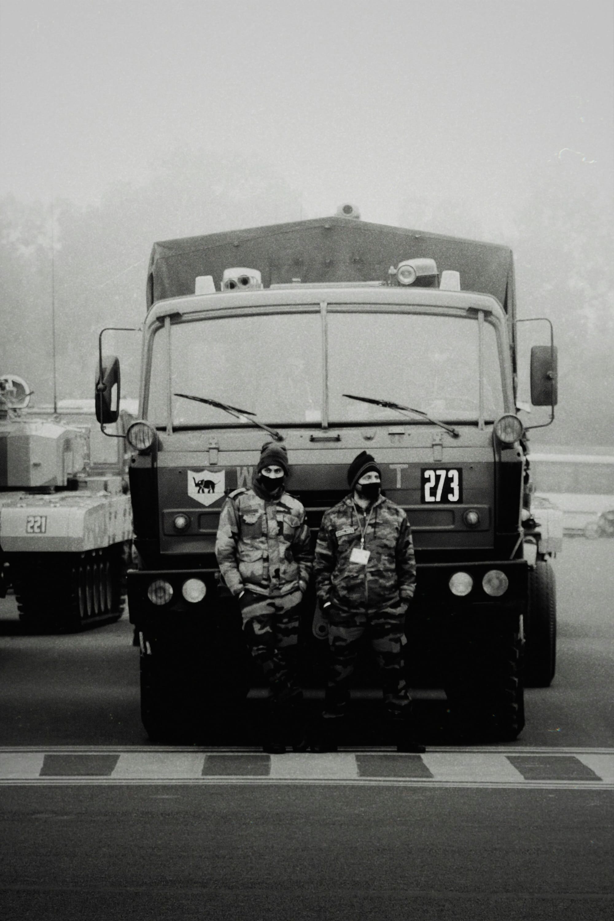 Two soldiers in front of a military truck in foggy weather