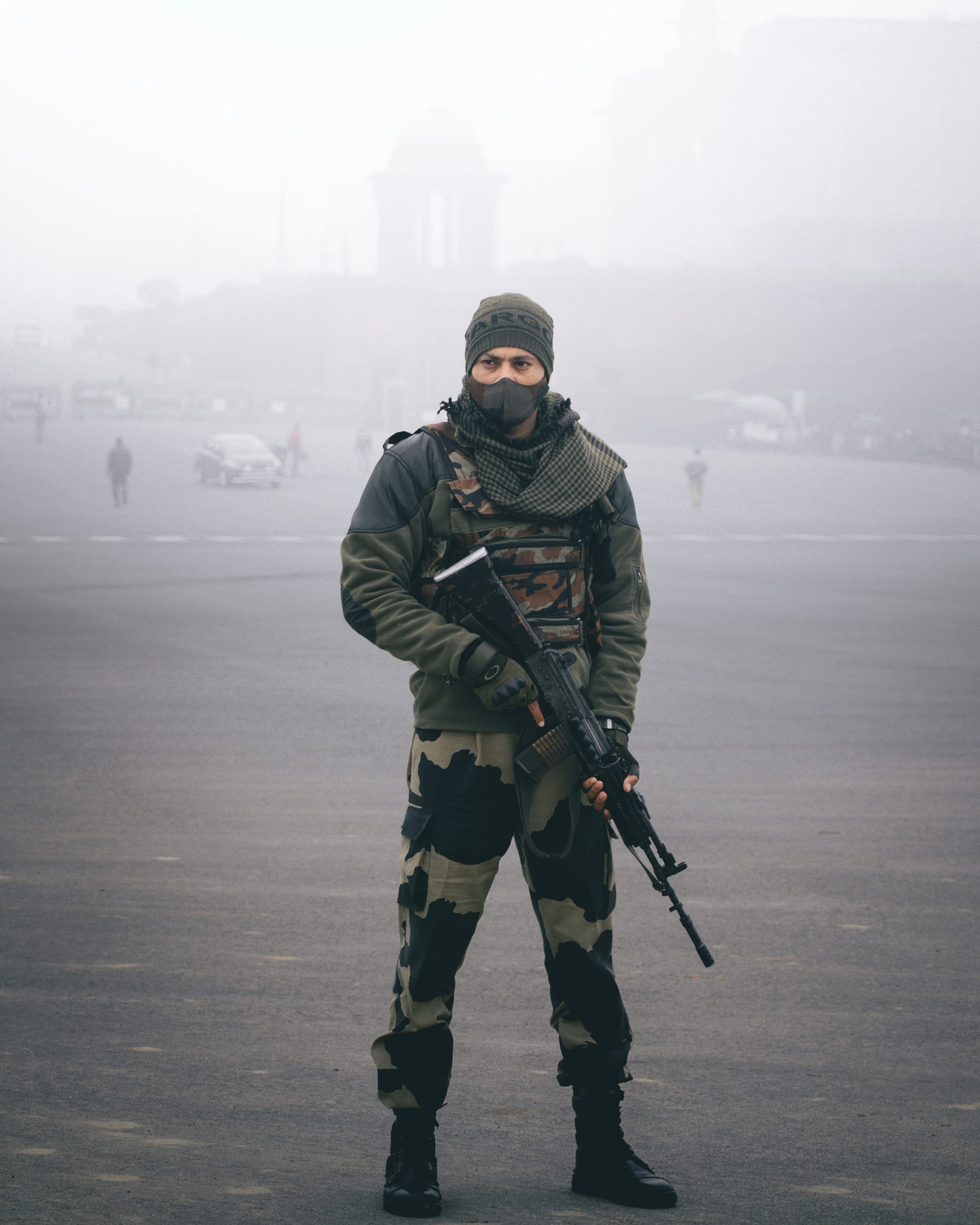Soldier in camouflage holding a rifle on a foggy street