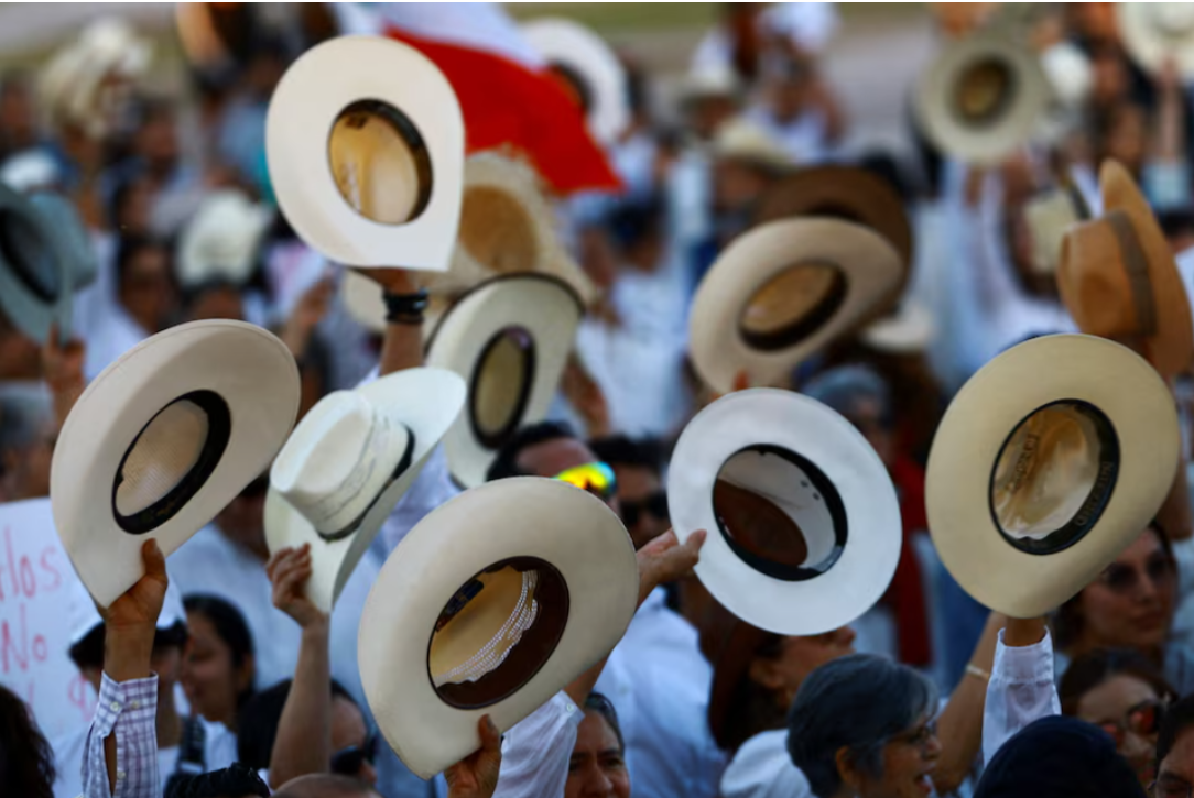 Protesters raise their hats during a demonstration against insecurity and corruption in the country, as well as over the recent killing of Uruapan mayor Carlos Manzo, in Ciudad Juarez, Mexico, November 15, 2025.