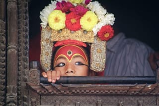 Wearing an elaborate headdress and painted eyes, Kumari Devi.