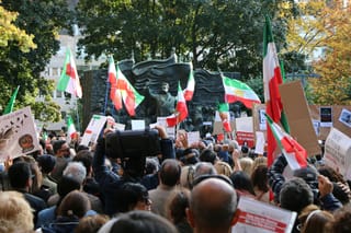 A protest march of civillians with the Iranian flag and placards