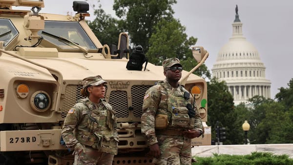National Guardsman leaning on a armoured vehicle with the congress building in the background
